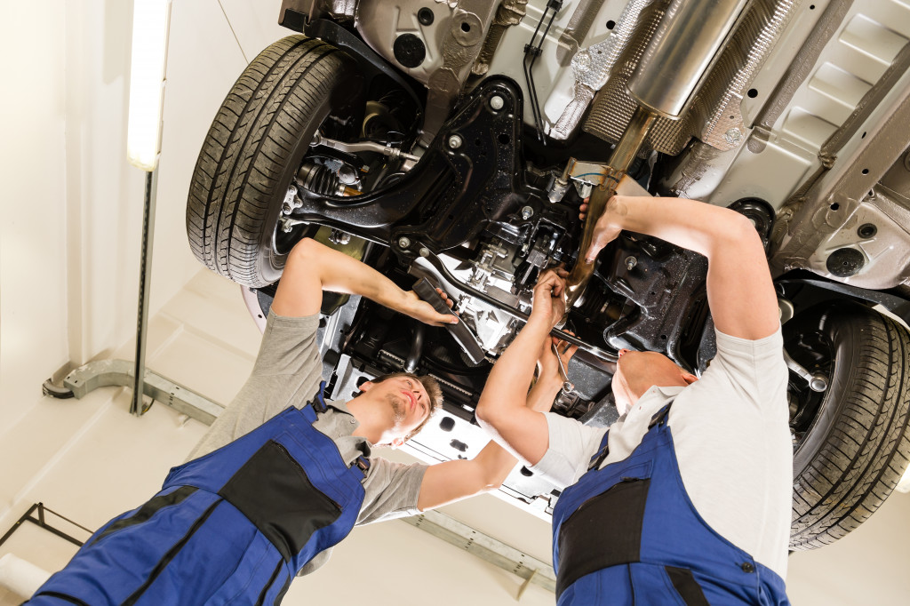 Two mechanics fixing a car at a shop.