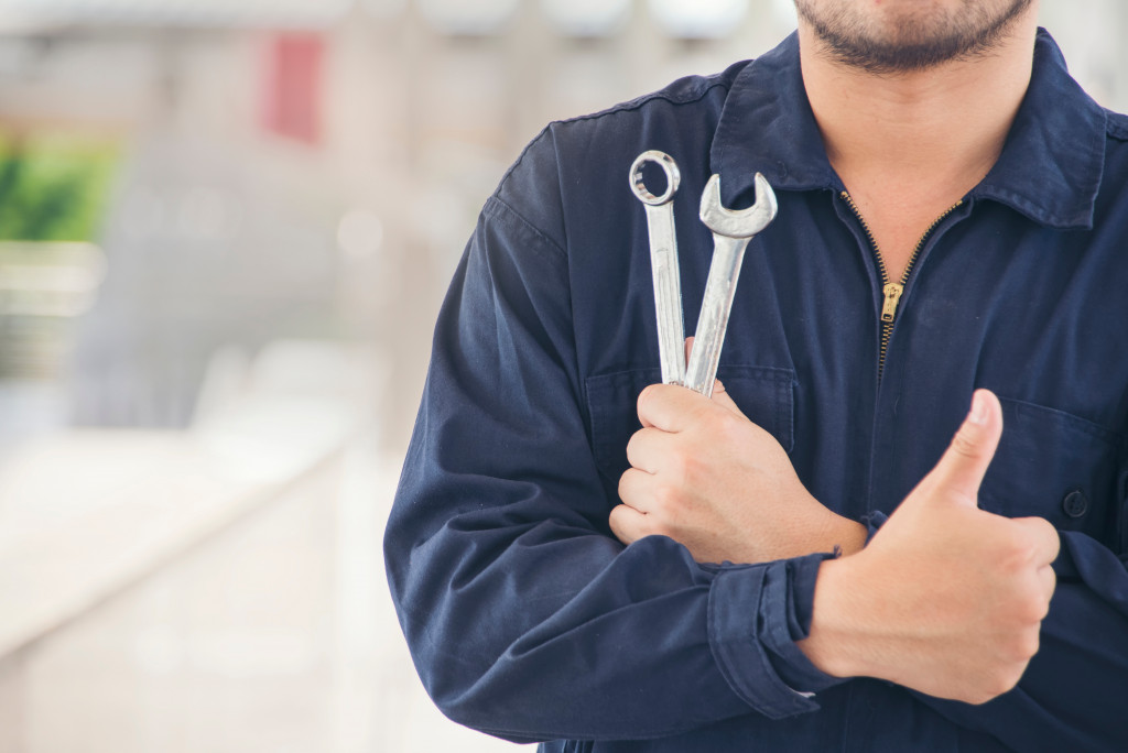 A mechanic holding tools and showing a thumbs-up